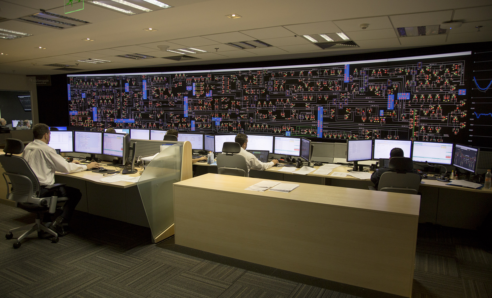 Inside a control room employees are sat in front of a PC
