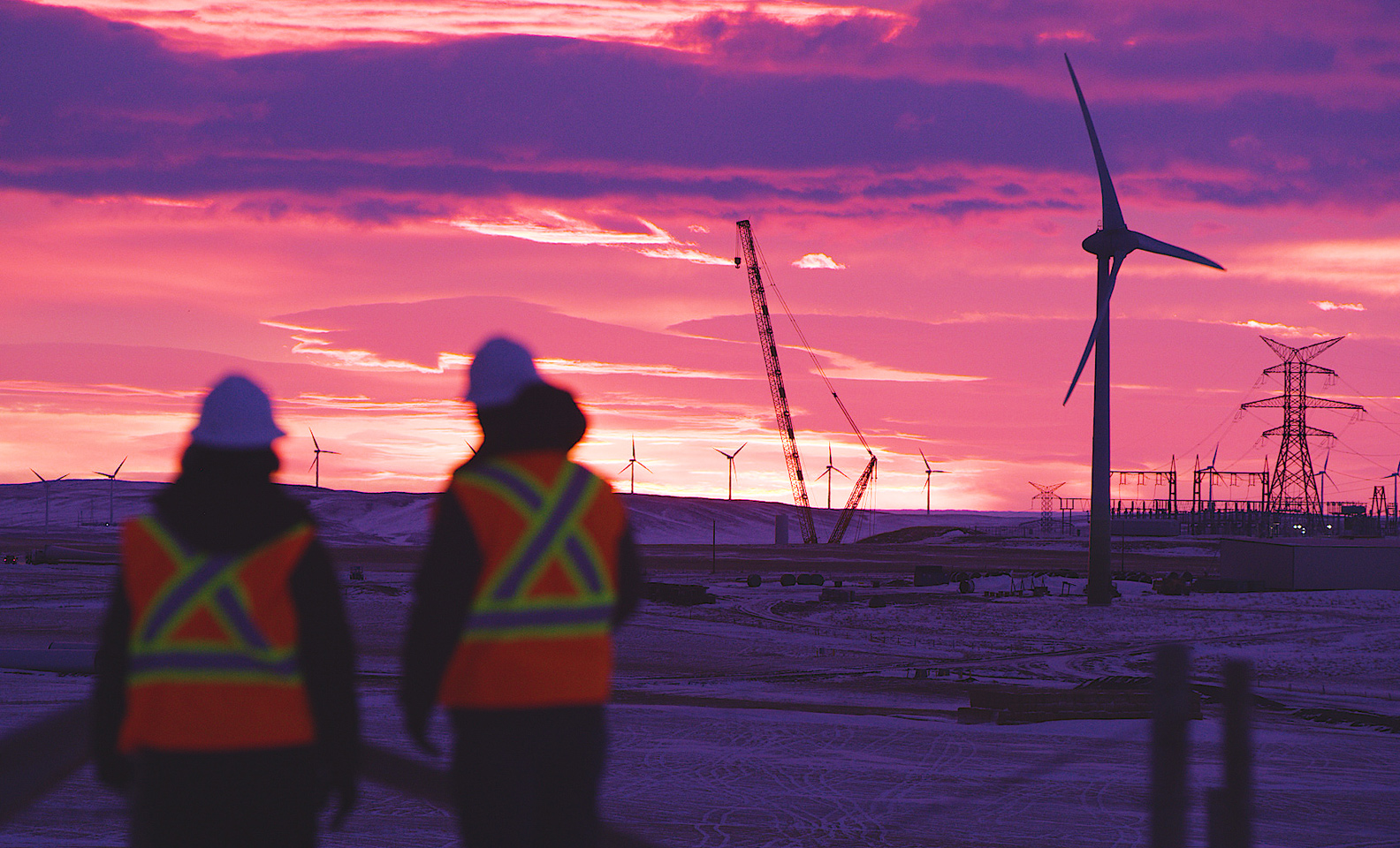 Two employees with wind turbines in the background