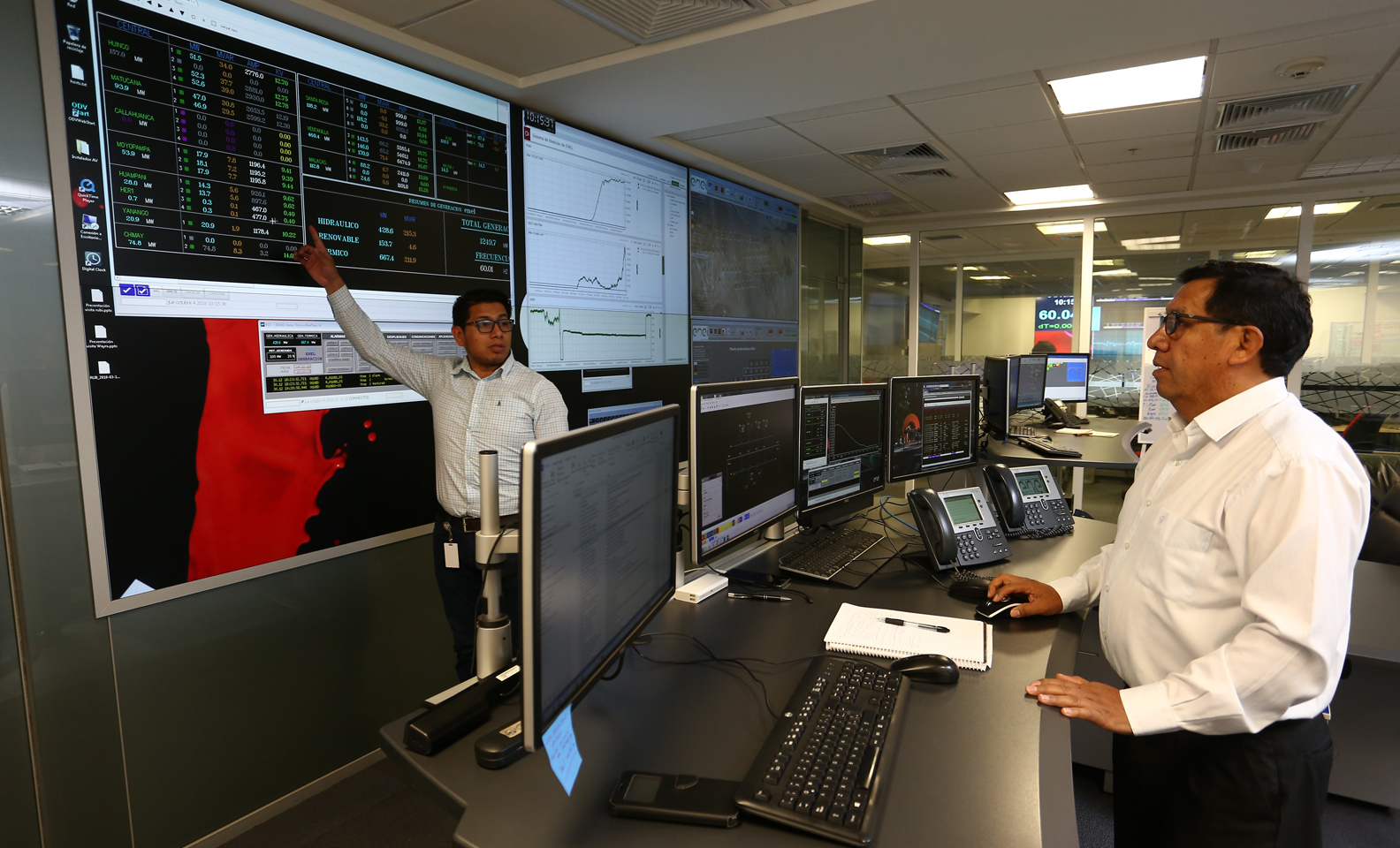 Technicians at work discussing the information shown on screens in a control center in Peru